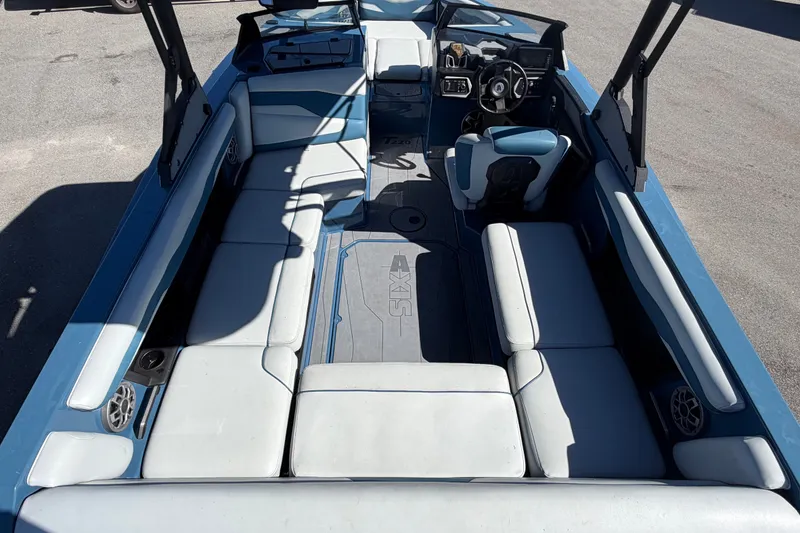 Slide: The Image of 2023 Axis T220 boat interior with blue and white seating, steering wheel, and speakers. - 15