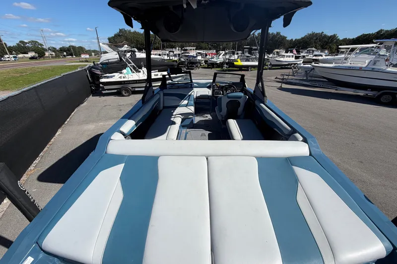 Slide: The Image of 2023 Axis T220 boat interior with blue and white seating, parked in a marina. - 13