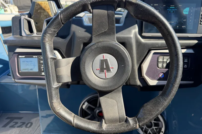 Slide: The Image of Steering wheel of a 2023 Axis T220 boat with dashboard controls. - 38