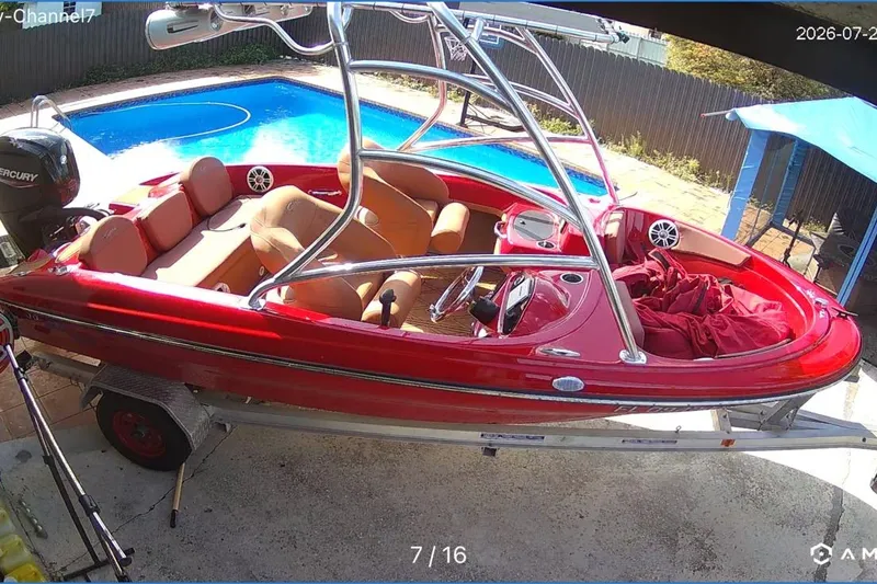 The Image of Red Cary 16 boat from 2000 on trailer, parked near a swimming pool. - 0