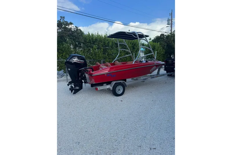 Slide: The Image of Red 2000 Cary 16 boat with Mercury outboard motor on trailer, parked outdoors. - 3