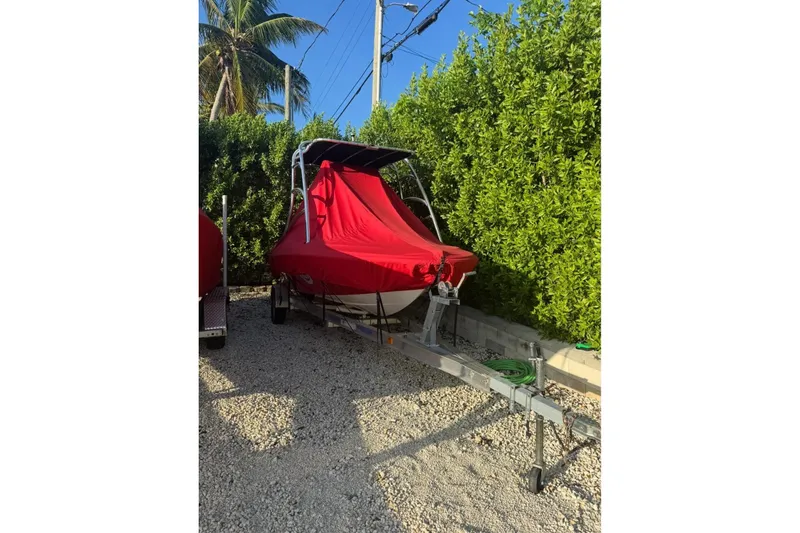 Slide: The Image of Red-covered Cary 16 boat from 2000 on a trailer, surrounded by greenery. - 5