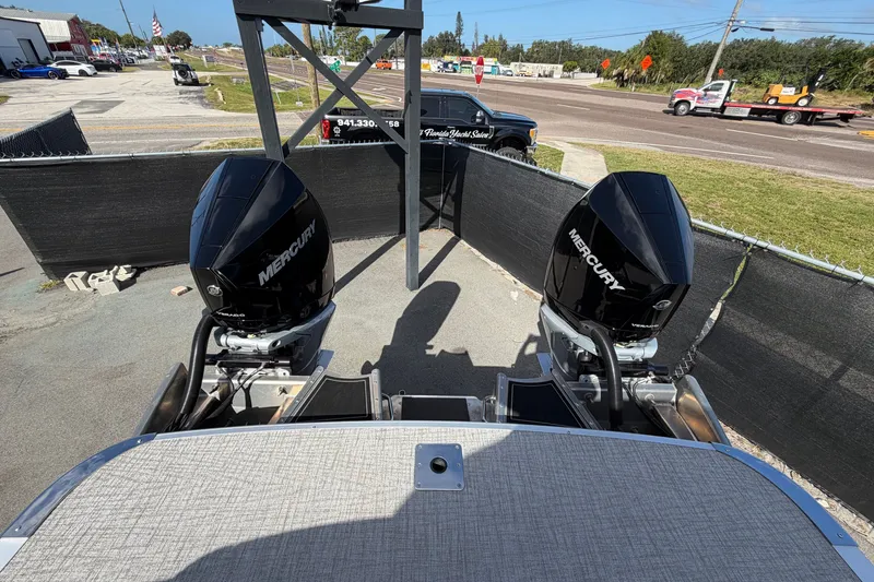 Slide: The Image of 2025 Avalon Excalibur LTD boat with dual Mercury outboard engines in a parking area. - 92