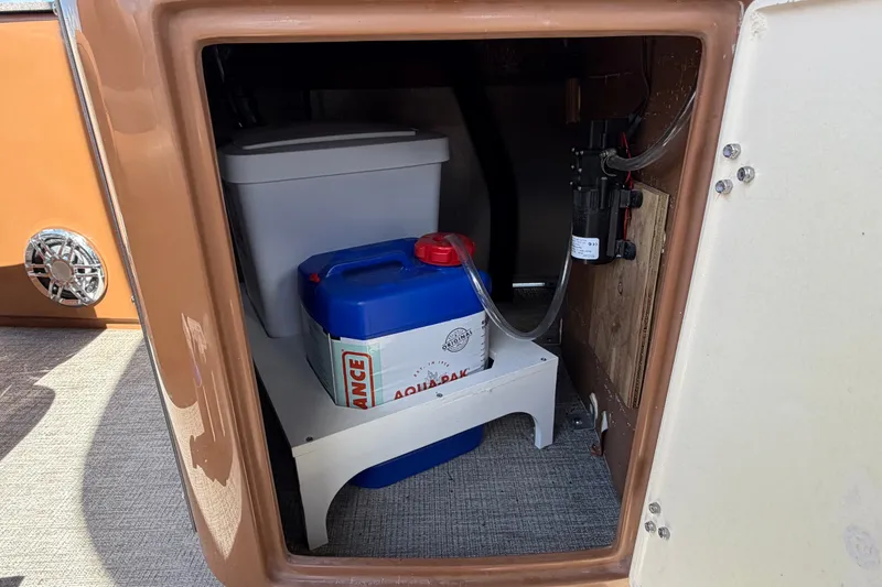 Slide: The Image of Storage compartment in 2025 Avalon Excalibur LTD Quad Lounge boat with water container and pump. - 32