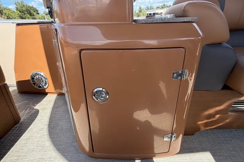 Slide: The Image of 2025 Avalon Excalibur LTD Quad Lounge boat interior with brown storage compartment and speaker. - 31