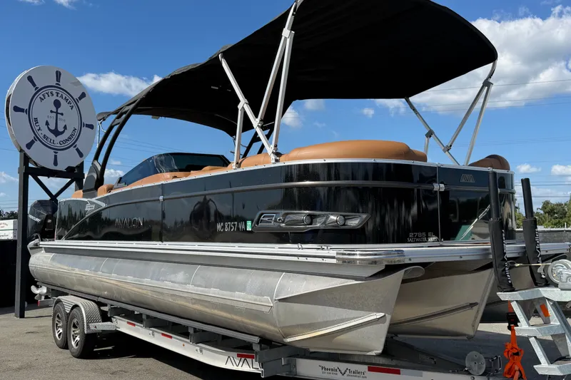 The Image of 2025 Avalon Excalibur LTD Quad Lounge boat on trailer, displayed outdoors. - 0