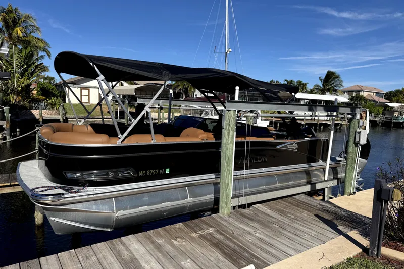The Image of 2025 Avalon Excalibur LTD Quad Lounge pontoon boat docked by waterfront. - 0