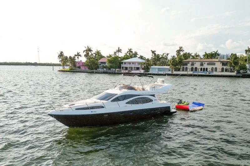 The Image of 1999 Azimut 52 yacht anchored near waterfront homes with palm trees. - 0