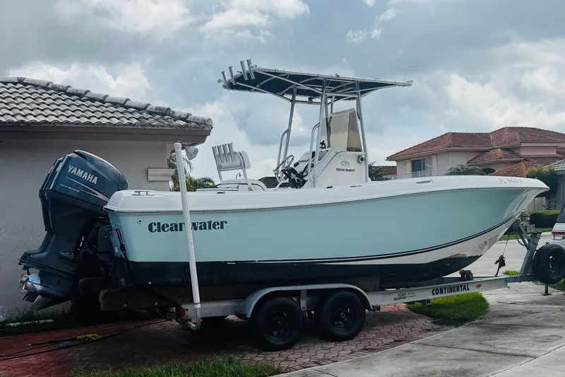 The Image of 2008 Clearwater 2300 Center Console boat on trailer with Yamaha engine, parked in residential area. - 0