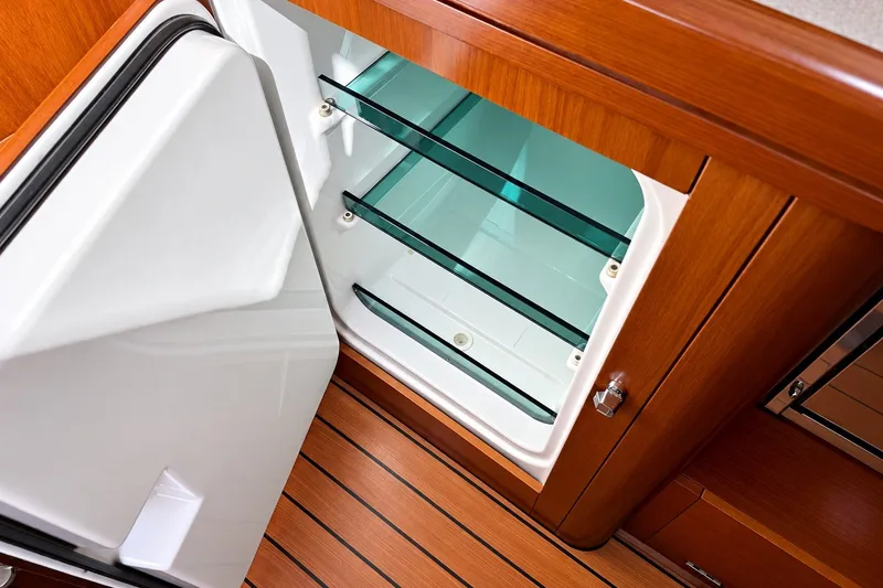 Slide: The Image of Open refrigerator in 2005 Beneteau Oceanis 473 yacht, showcasing wooden interior and glass shelves. - 15
