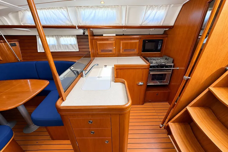 Slide: The Image of Interior of 2005 Beneteau Oceanis 473 yacht, featuring a modern kitchen and dining area. - 14