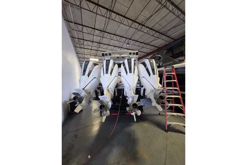 Slide: The Image of Four powerful outboard motors on a 2021 MTI 42 v boat in a warehouse setting. - 1