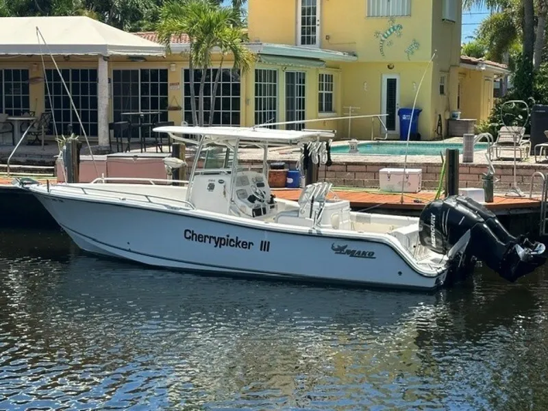 The Image of A 2018 Mako 284 boat docked in front of a yellow house. - 1