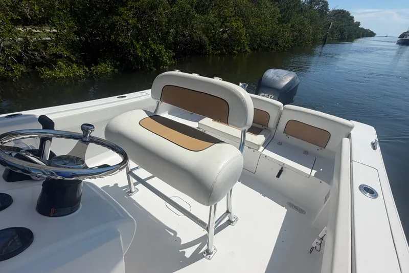Slide: The Image of 2013 Sportsman Heritage 229 Center Console boat interior with steering wheel and seating, near waterway. - 19