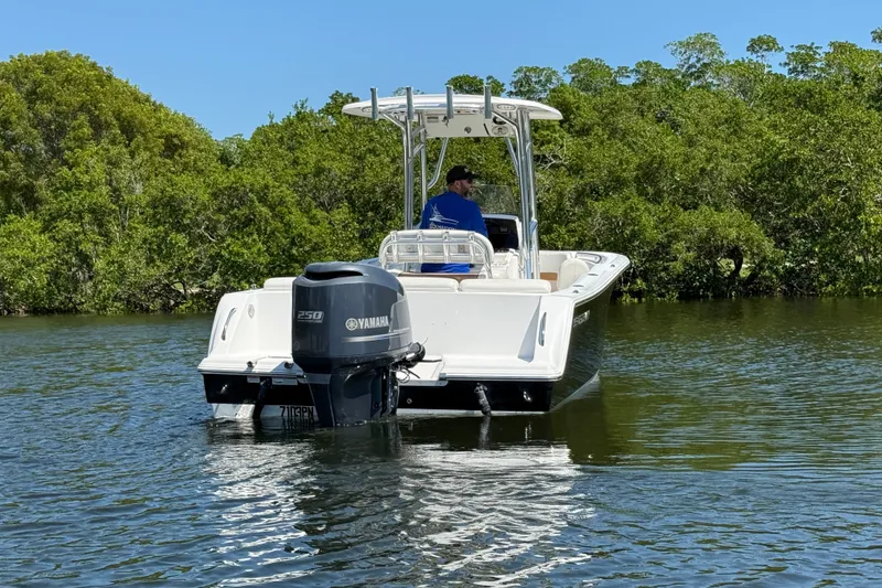 Slide: The Image of 2013 Sportsman Heritage 229 Center Console boat on calm water, surrounded by lush greenery. - 5