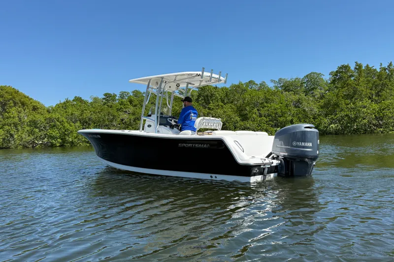 Slide: The Image of 2013 Sportsman Heritage 229 Center Console boat on calm water, surrounded by lush greenery. - 3