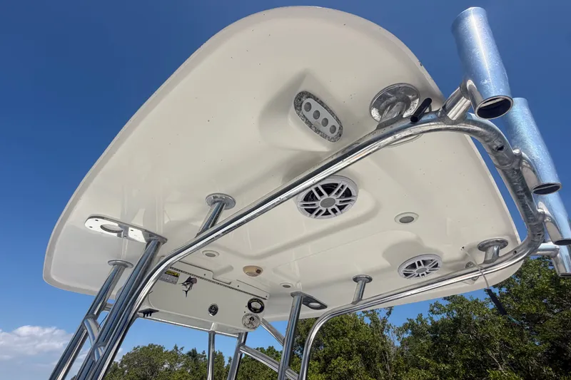 Slide: The Image of 2013 Sportsman Heritage 229 Center Console T-top with speakers and rod holders against blue sky. - 23
