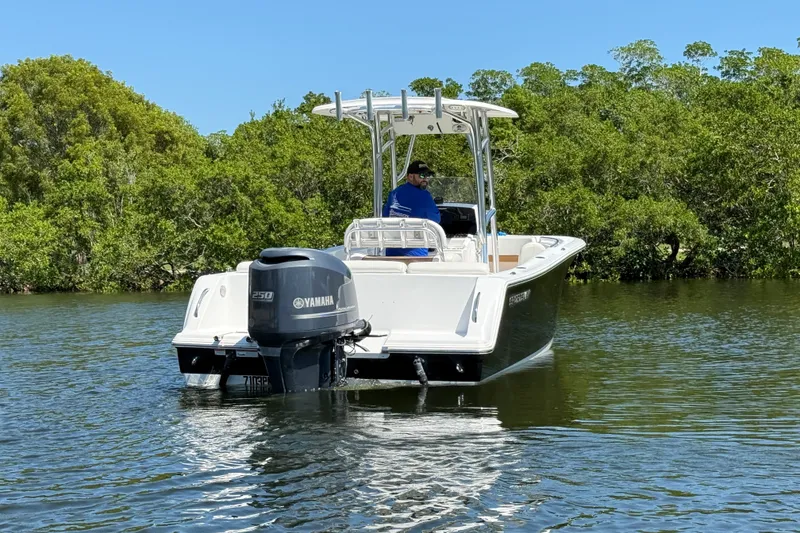 Slide: The Image of 2013 Sportsman Heritage 229 Center Console boat on calm water, surrounded by lush greenery. - 6