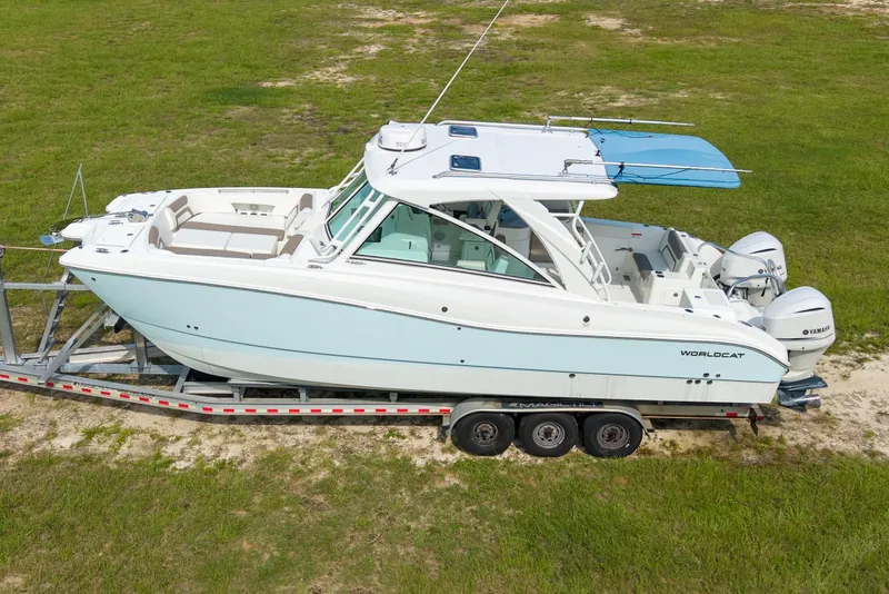 Slide: The Image of 2020 World Cat 320 DC boat on trailer, side view, parked on grass. - 4