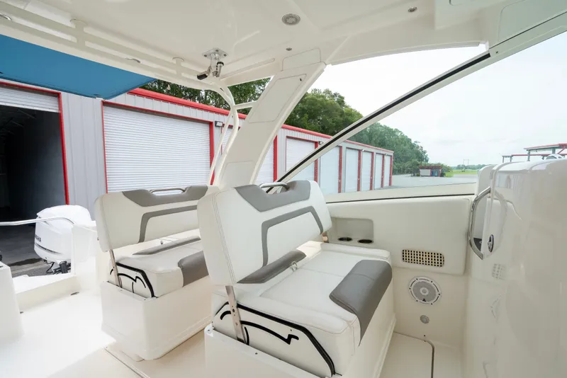 Slide: The Image of 2020 World Cat 320 DC boat interior with white seating and storage units in a marina setting. - 10