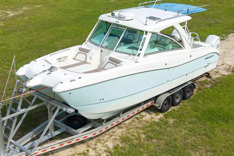 Slide: The Image of 2020 World Cat 320 DC boat on trailer, parked on grassy area. - 1