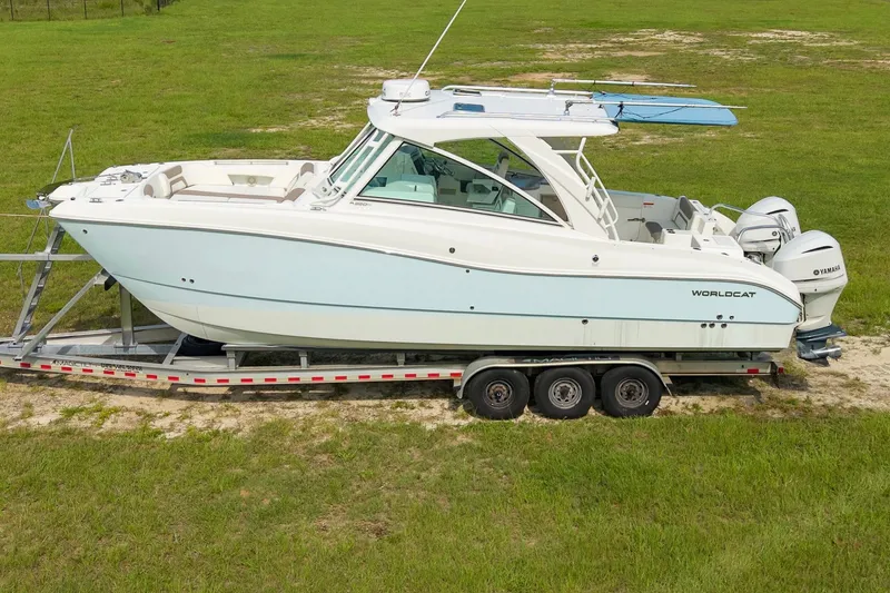 Slide: The Image of 2020 World Cat 320 DC boat on trailer, parked on grassy field. - 3