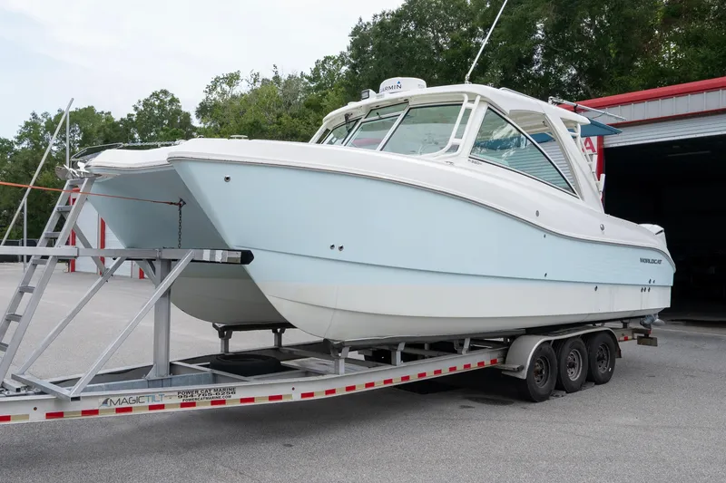 Slide: The Image of 2020 World Cat 320 DC boat on trailer, parked outdoors near a garage. - 5