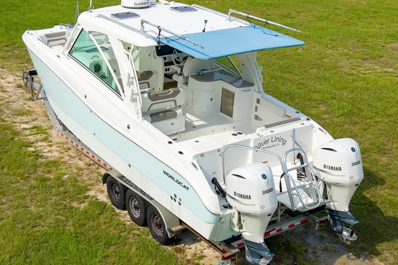 Slide: The Image of 2020 World Cat 320 DC boat with Yamaha engines on a trailer, parked on grass. - 2