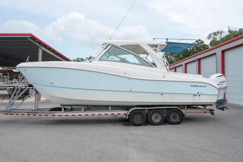 The Image of 2020 World Cat 320 DC boat on trailer, parked near storage units. - 0