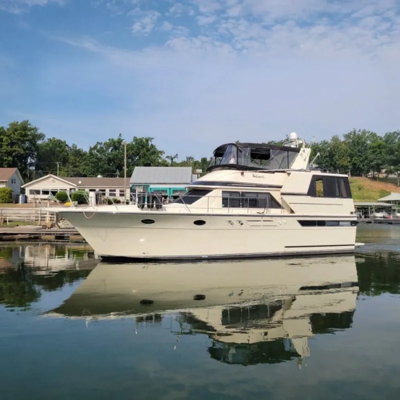 The Image of 1988 Californian 45 Motor Yacht docked on calm water, surrounded by trees and buildings. - 0