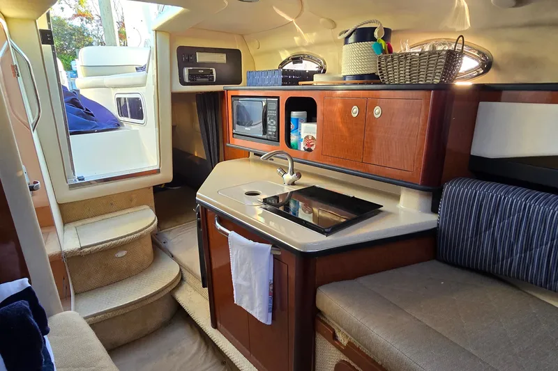 Slide: The Image of Interior of 2005 Sea Ray Sundancer 260 boat with kitchenette and seating area. - 14