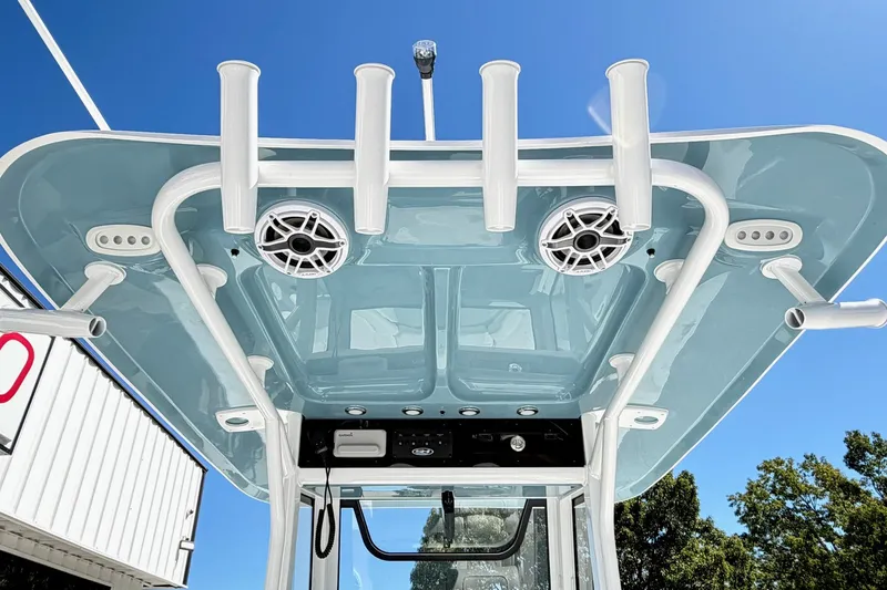 Slide: The Image of 2027 Sea Hunt BX28 boat T-top with rod holders and speakers against blue sky. - 7