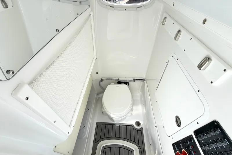 Slide: The Image of Interior of 2027 Sea Hunt BX28 boat, featuring a compact marine toilet and storage compartments. - 29
