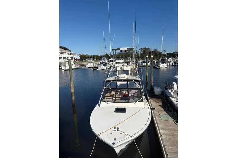 Slide: The Image of 1995 Carolina Classic 28 boat docked at a marina under clear blue skies. - 18