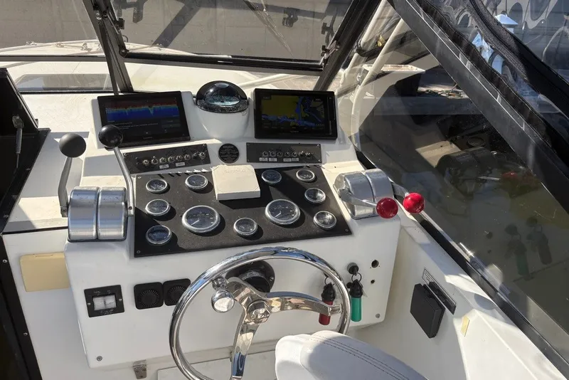 Slide: The Image of 1995 Carolina Classic 28 boat dashboard with steering wheel and navigation instruments. - 2