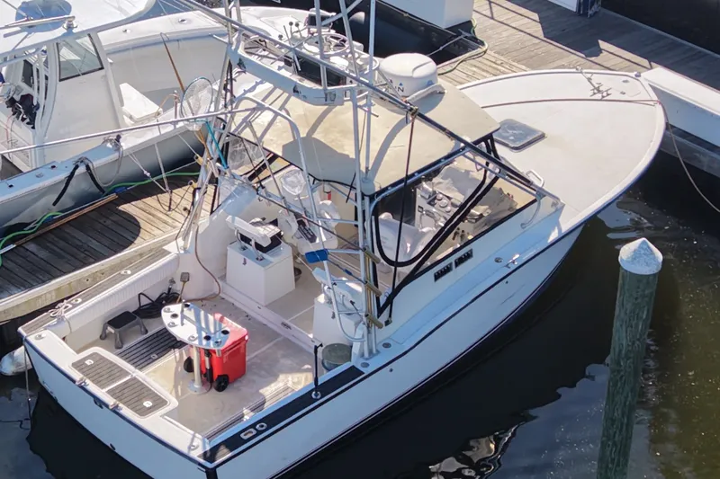 Slide: The Image of 1995 Carolina Classic 28 boat docked at marina, featuring fishing equipment and spacious deck. - 0