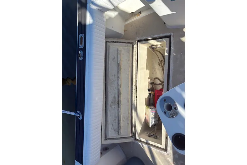 Slide: The Image of Open storage compartment on a 1995 Carolina Classic 28 boat, showing tools and equipment. - 33