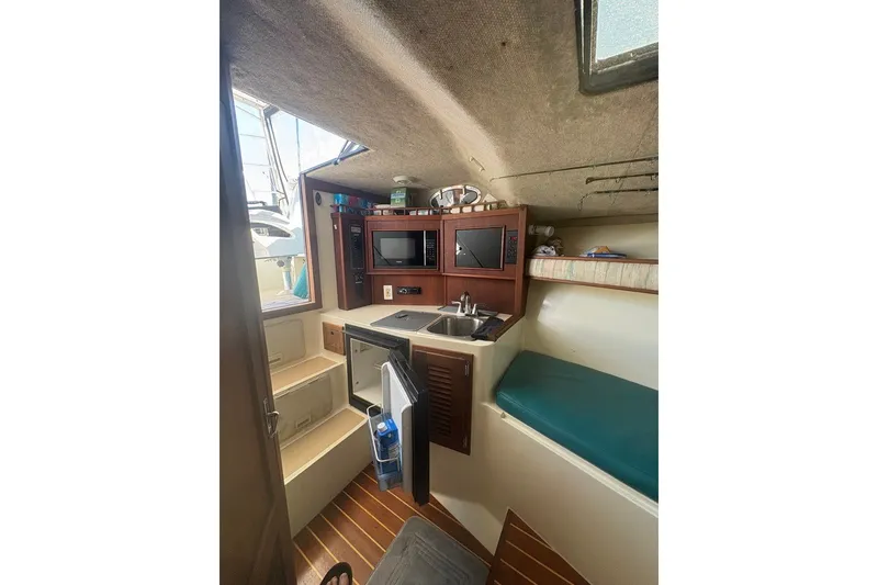Slide: The Image of Interior of a 1995 Carolina Classic 28 boat, featuring a compact kitchen and seating area. - 38
