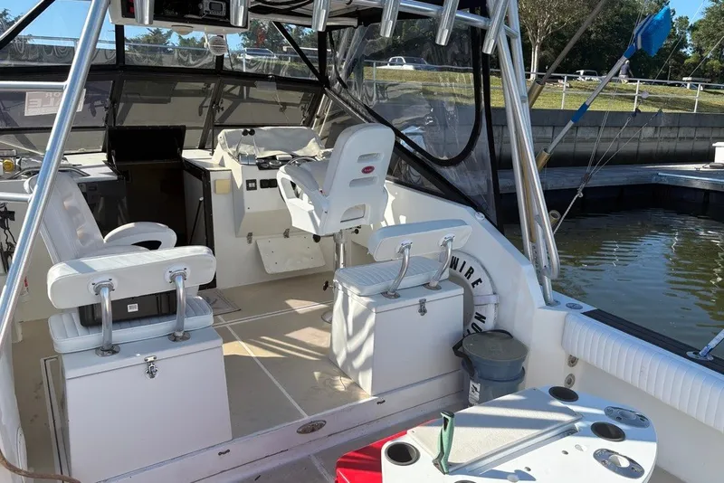 Slide: The Image of 1995 Carolina Classic 28 boat interior with seating and fishing equipment at a marina. - 16
