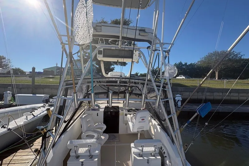 Slide: The Image of 1995 Carolina Classic 28 boat docked, featuring fishing equipment and a clear blue sky. - 12
