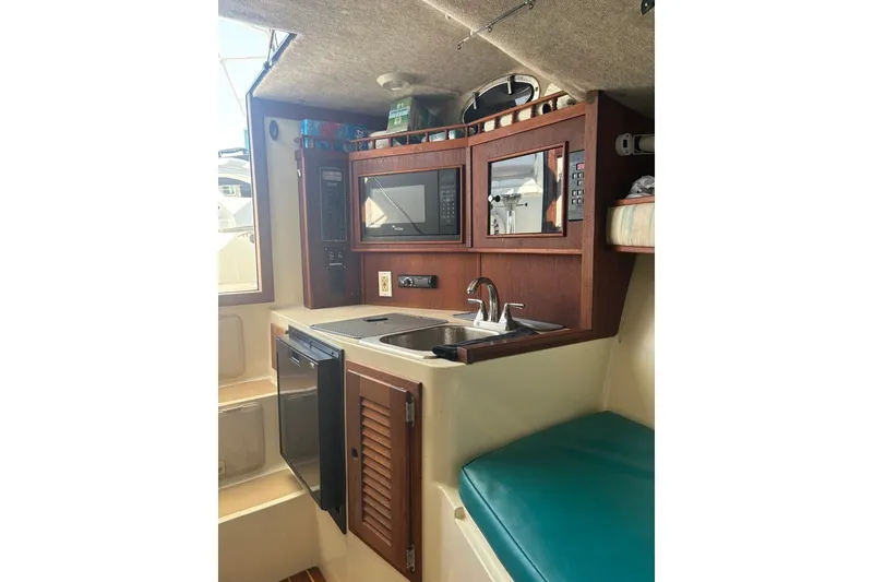 Slide: The Image of 1995 Carolina Classic 28 boat interior with kitchenette, featuring sink, microwave, and compact fridge. - 39