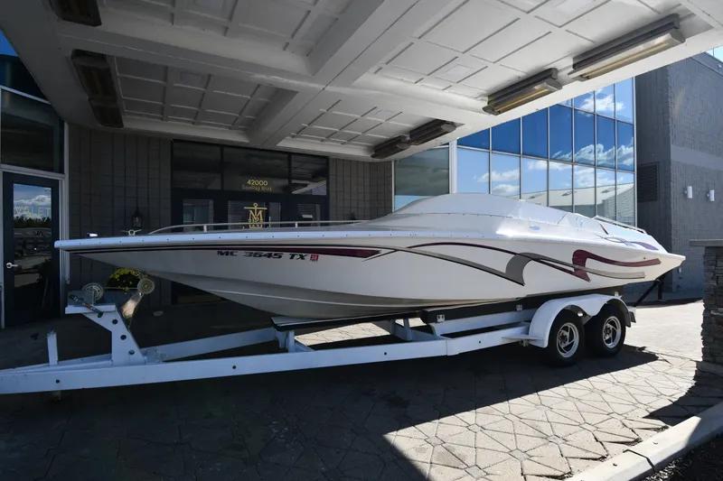 The Image of 1995 Fountain 24 Competition boat on trailer, parked outside modern building. - 1