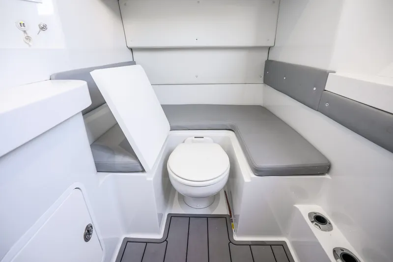 Slide: The Image of 2024 Conch 41 boat interior with toilet and cushioned seating in white and gray. - 48