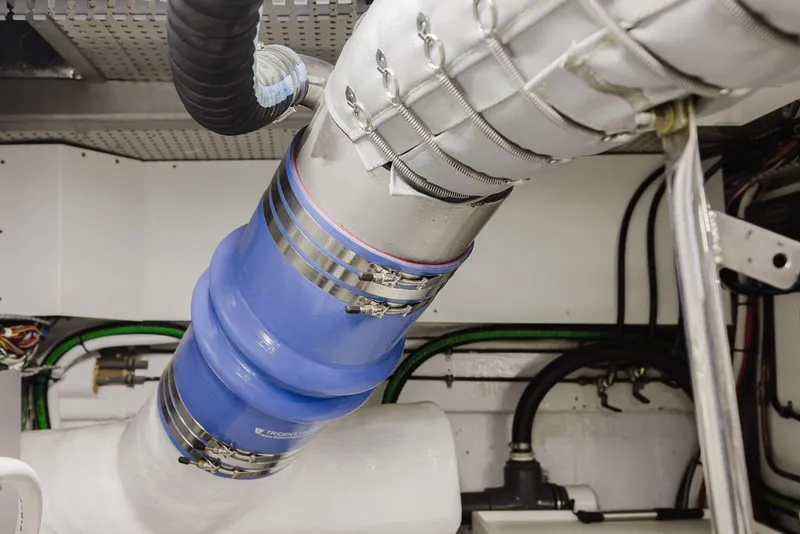 Slide: The Image of Engine room of 1999 Ocean Alexander 680 Classicco yacht, featuring blue exhaust hose and metal clamps. - 87