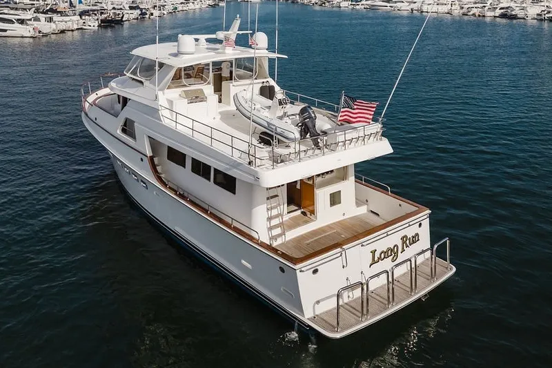 Slide: The Image of 1999 Ocean Alexander 680 Classicco yacht on water, featuring spacious deck and American flags. - 117
