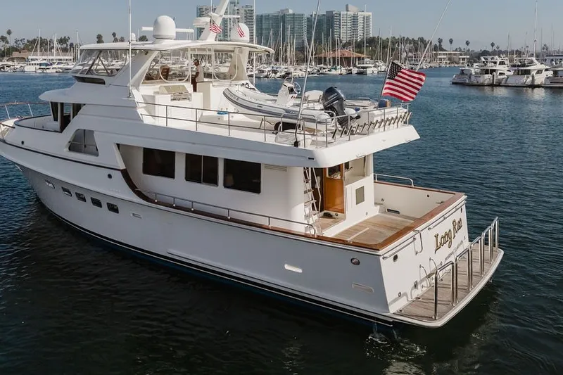 Slide: The Image of 1999 Ocean Alexander 680 Classicco yacht docked in marina, featuring sleek design and American flag. - 118