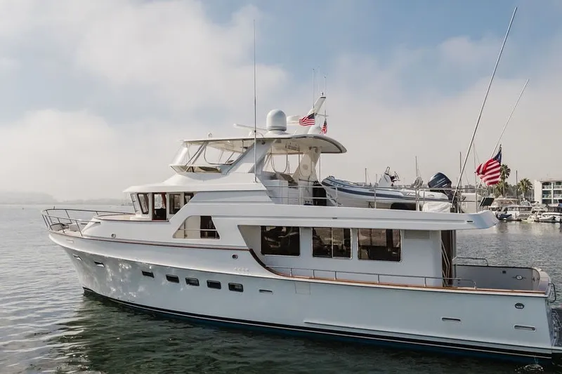 Slide: The Image of 1999 Ocean Alexander 680 Classicco yacht on calm water, featuring sleek design and American flags. - 123