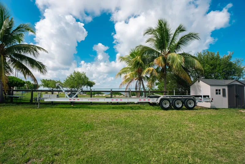 Slide: The Image of Trailer for 2023 Front Runner 39 Center Console, parked near palm trees and shed. - 83
