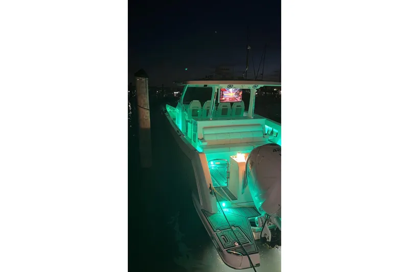 Slide: The Image of 2020 Regal 38 SAV boat illuminated with green lights at night, docked in a marina. - 55