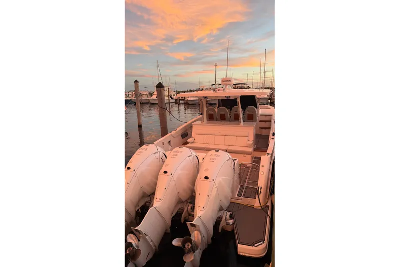 Slide: The Image of 2020 Regal 38 SAV boat docked at sunset with triple outboard engines. - 24